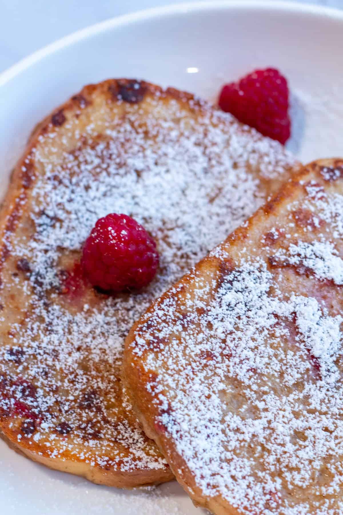Raspberry french toast served with powdered sugar and raspberries on top