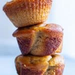 Almond flour banana muffins stacked on top of each other on a white surface
