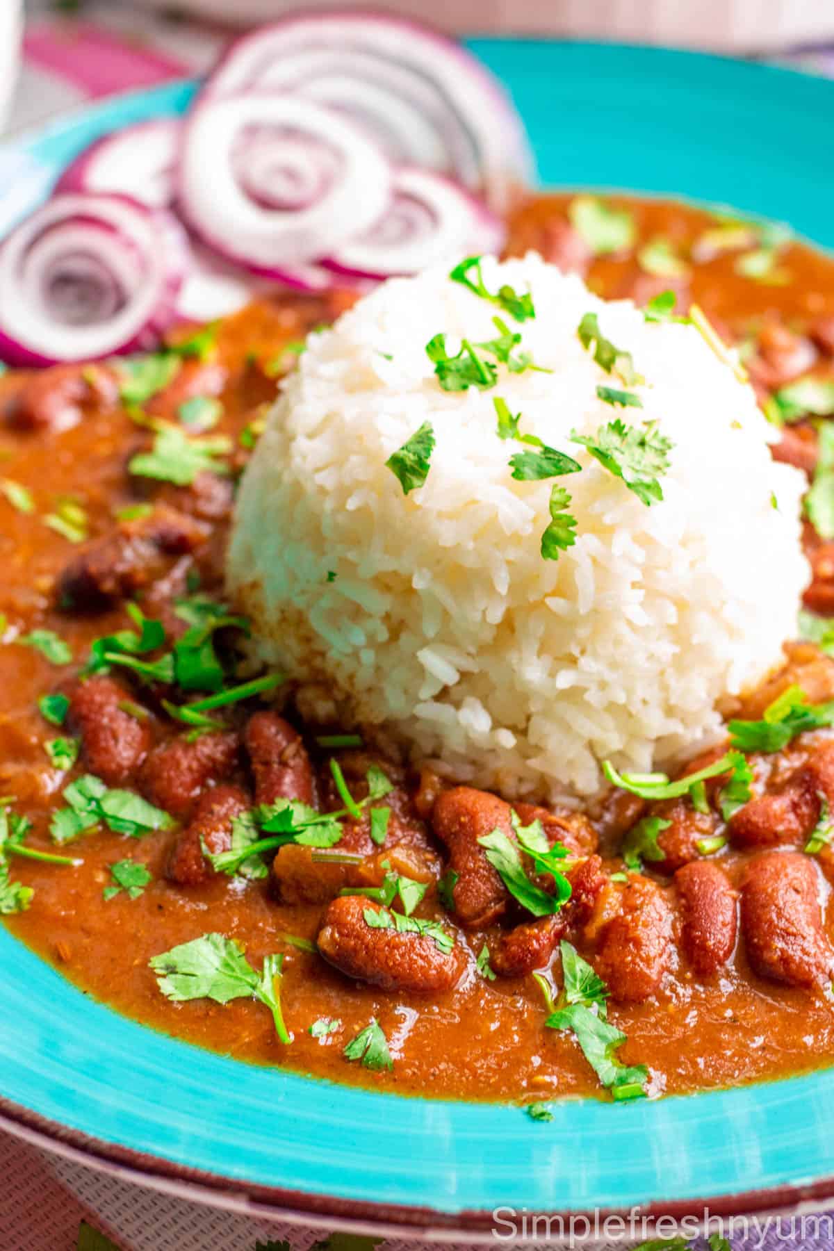 Close up image on Rajma masala served with white rice in a blue plate with cilantro garnished on top