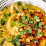 spicy chole hummus in a black and white bowl.